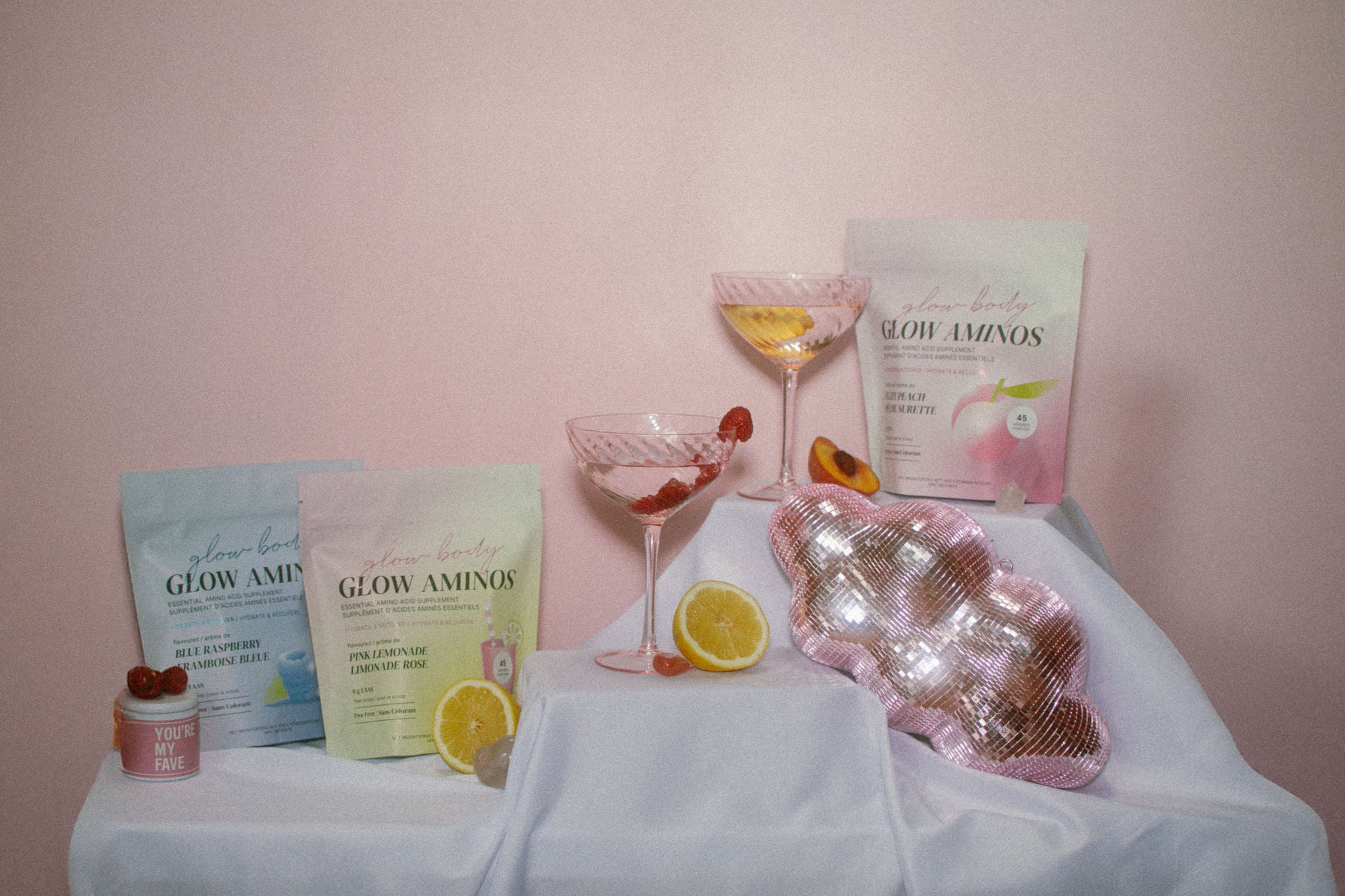 Glow Aminos products on a table with a pink background